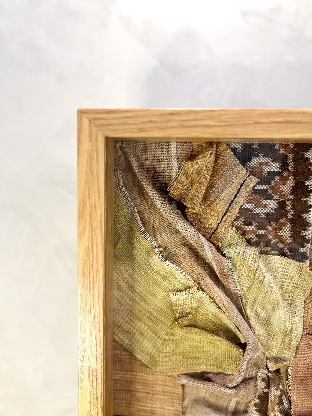 Textile sample with a pattern in a wooden frame on a light background