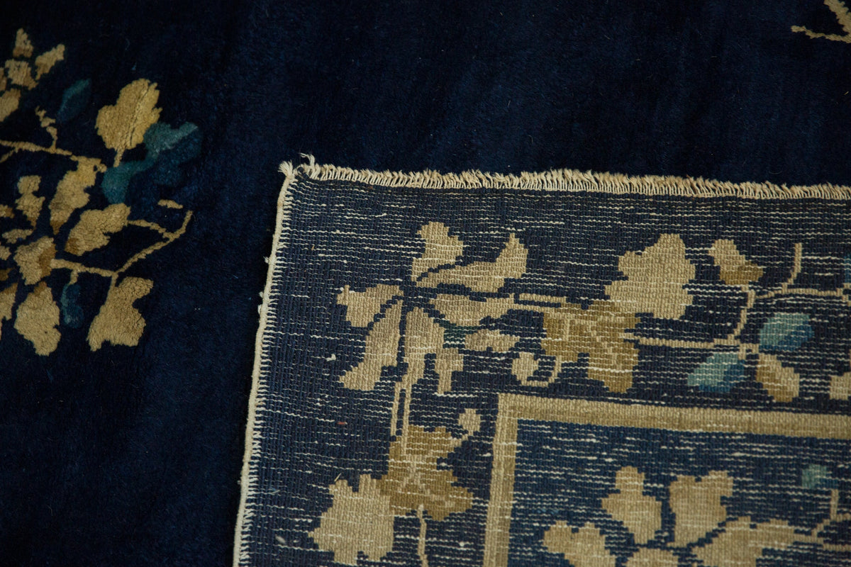 Close-up of a dark blue rug with intricate gold floral patterns