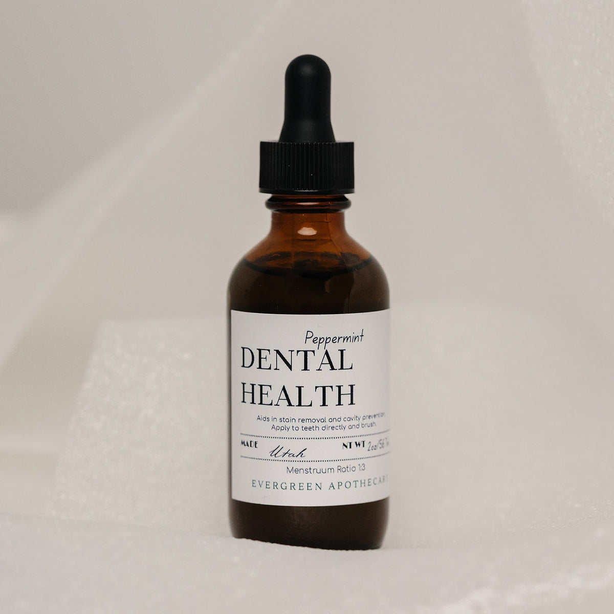Bottle of dental health product with dropper on a neutral background