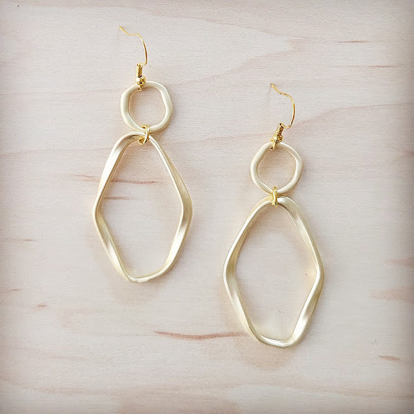 Gold hoop earrings on a light wooden surface