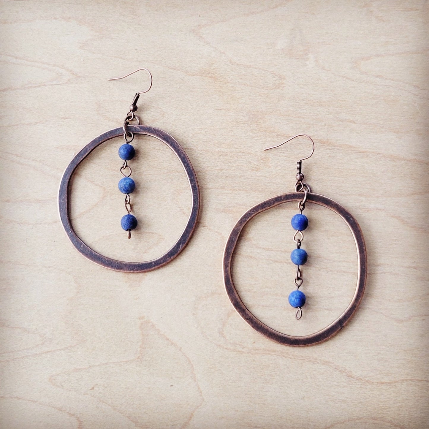 Pair of hoop earrings with blue beads on a beige surface