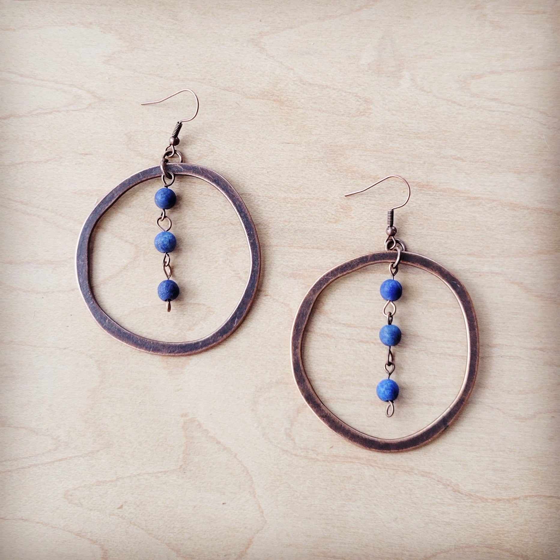 Pair of hoop earrings with blue beads on a beige surface