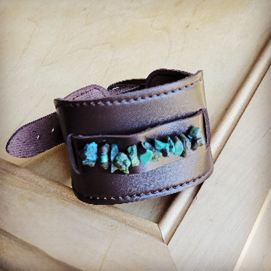 Brown leather cuff with turquoise stones on a wooden surface