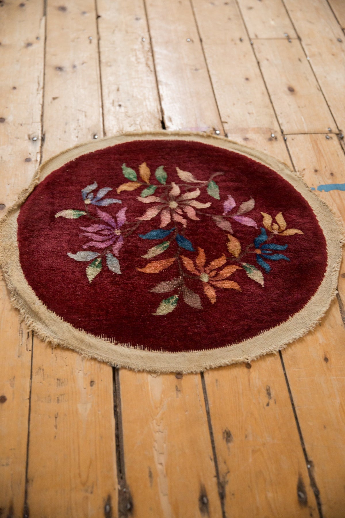 Round embroidered rug with floral patterns on a wooden floor