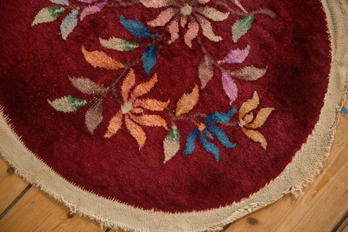 Round red rug with floral patterns on a wooden floor