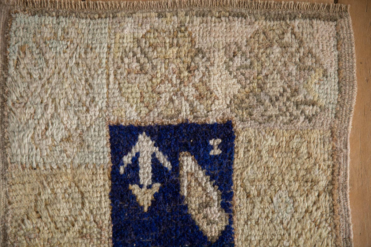 Textile with a blue square featuring white abstract designs on a beige background