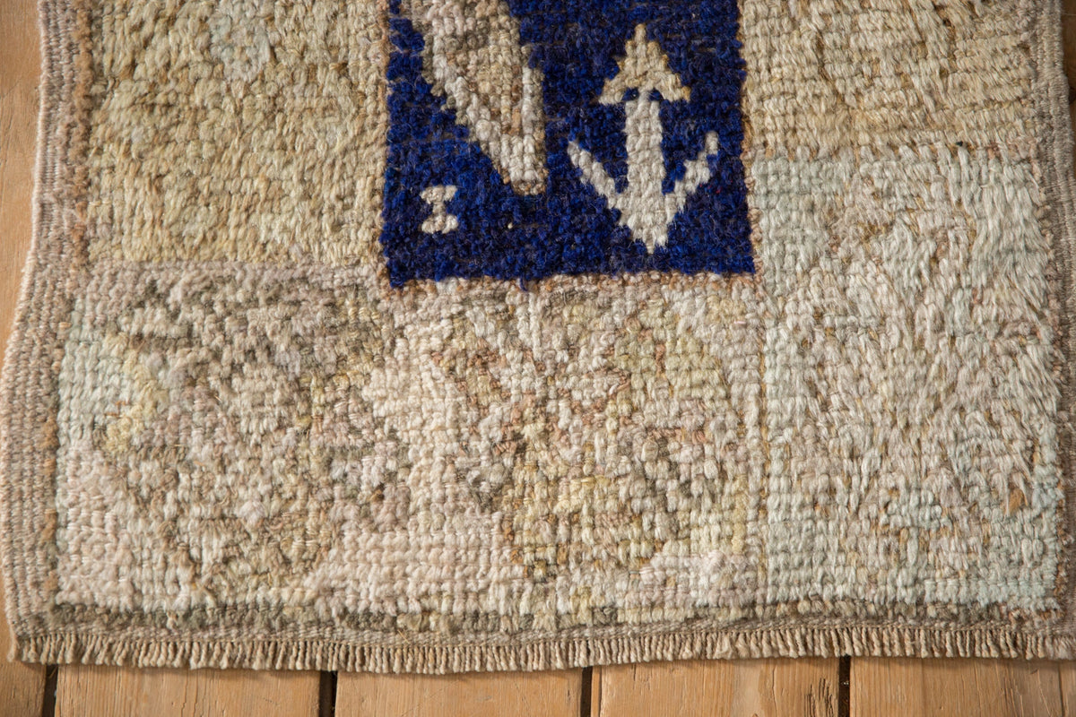 Textured rug with a blue square featuring an anchor design on a wooden floor.