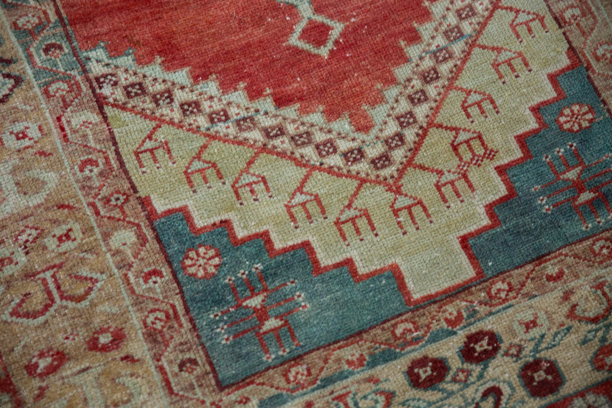 Close-up of a patterned rug with geometric designs in red, blue, and beige.