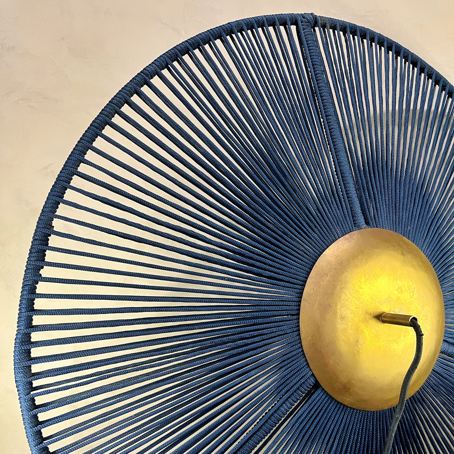 Decorative wall light with blue woven design and gold fixture on a beige background