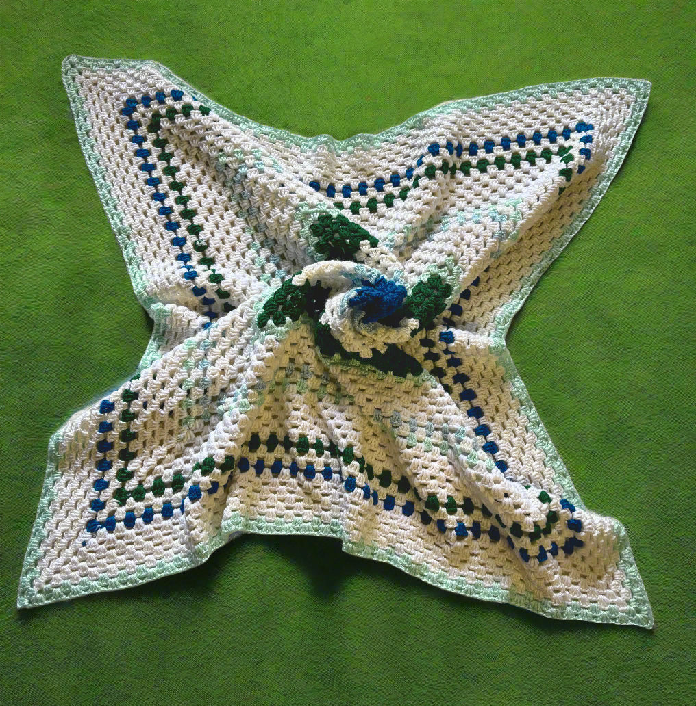 A handmade crochet afghan with a geometric pattern in red, white, and brown colors laid out on a flat surface.