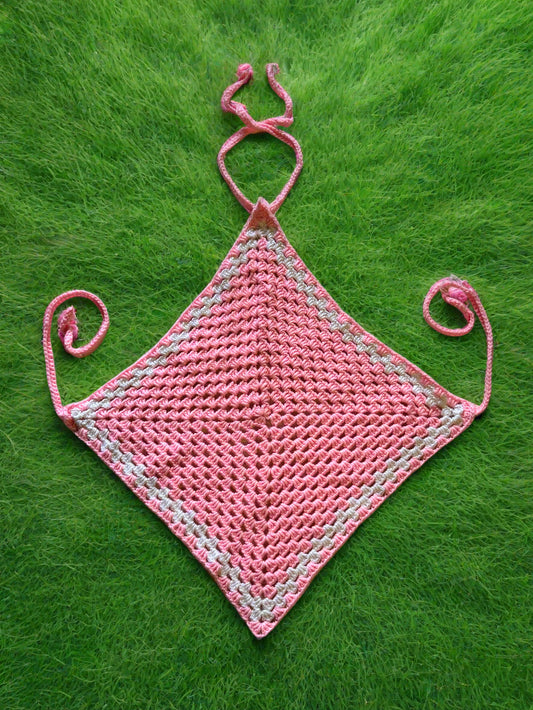 A pink crochet diamond-shaped top with adjustable straps, laid flat on a textured surface.