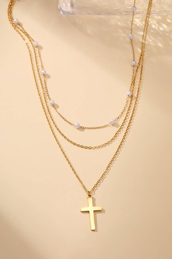 Gold necklace with cross pendant on a beige background
