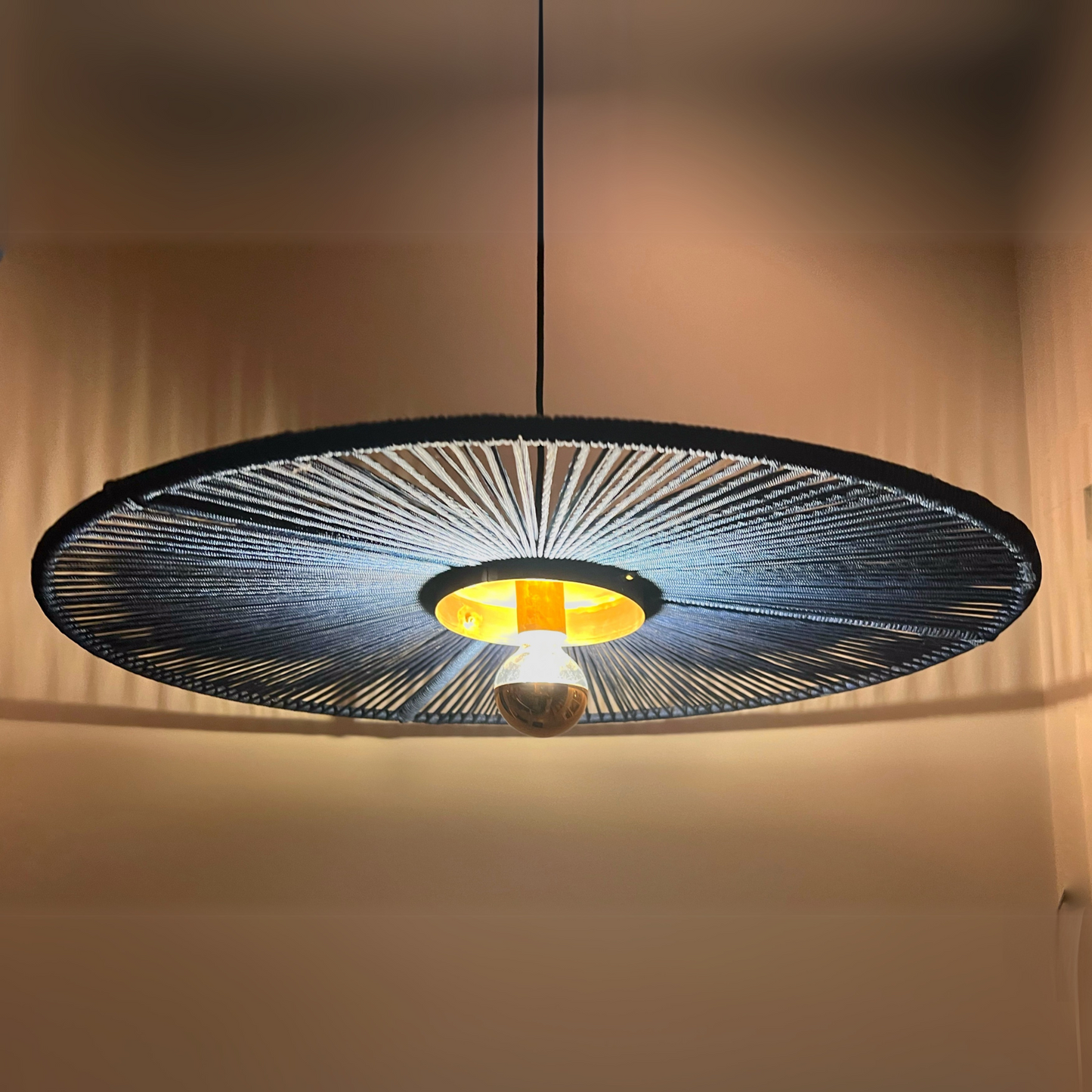Modern pendant light with black woven design on a neutral background