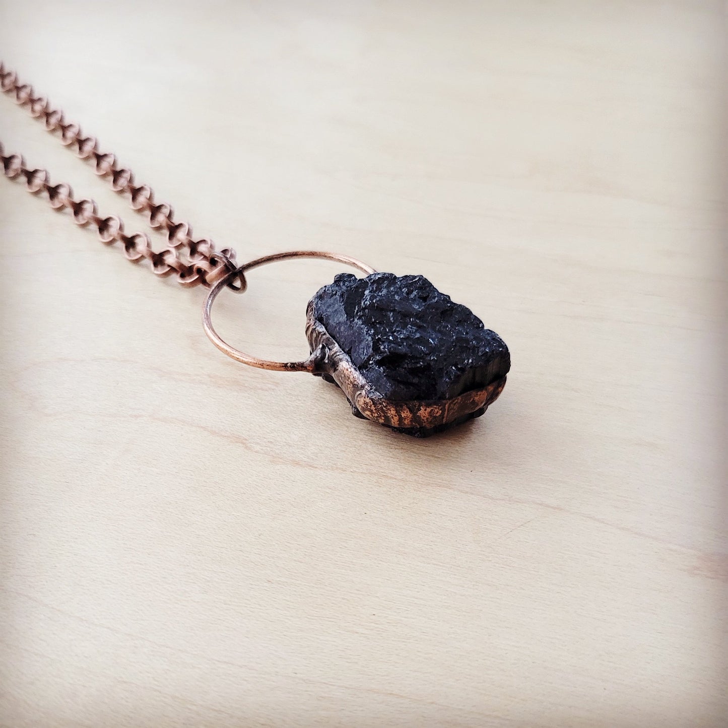 Necklace with a dark stone pendant on a light wooden surface