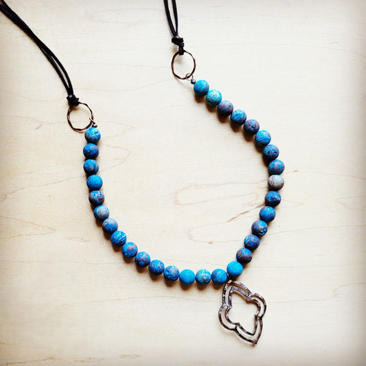Blue beaded necklace with a silver heart pendant on a light wooden surface