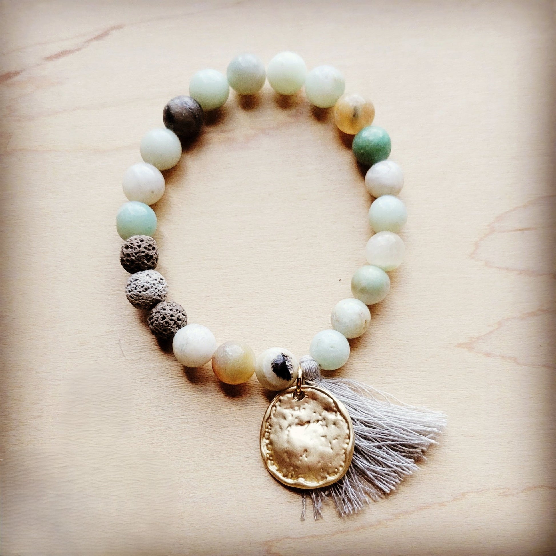 Beaded bracelet with a gold pendant and tassel on a beige background