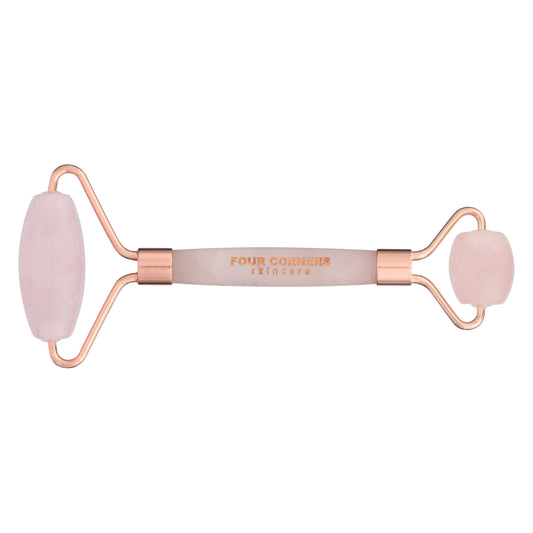 A two-sided rose quartz face roller with rose gold accents and 'Four Corners' branding in the center.
