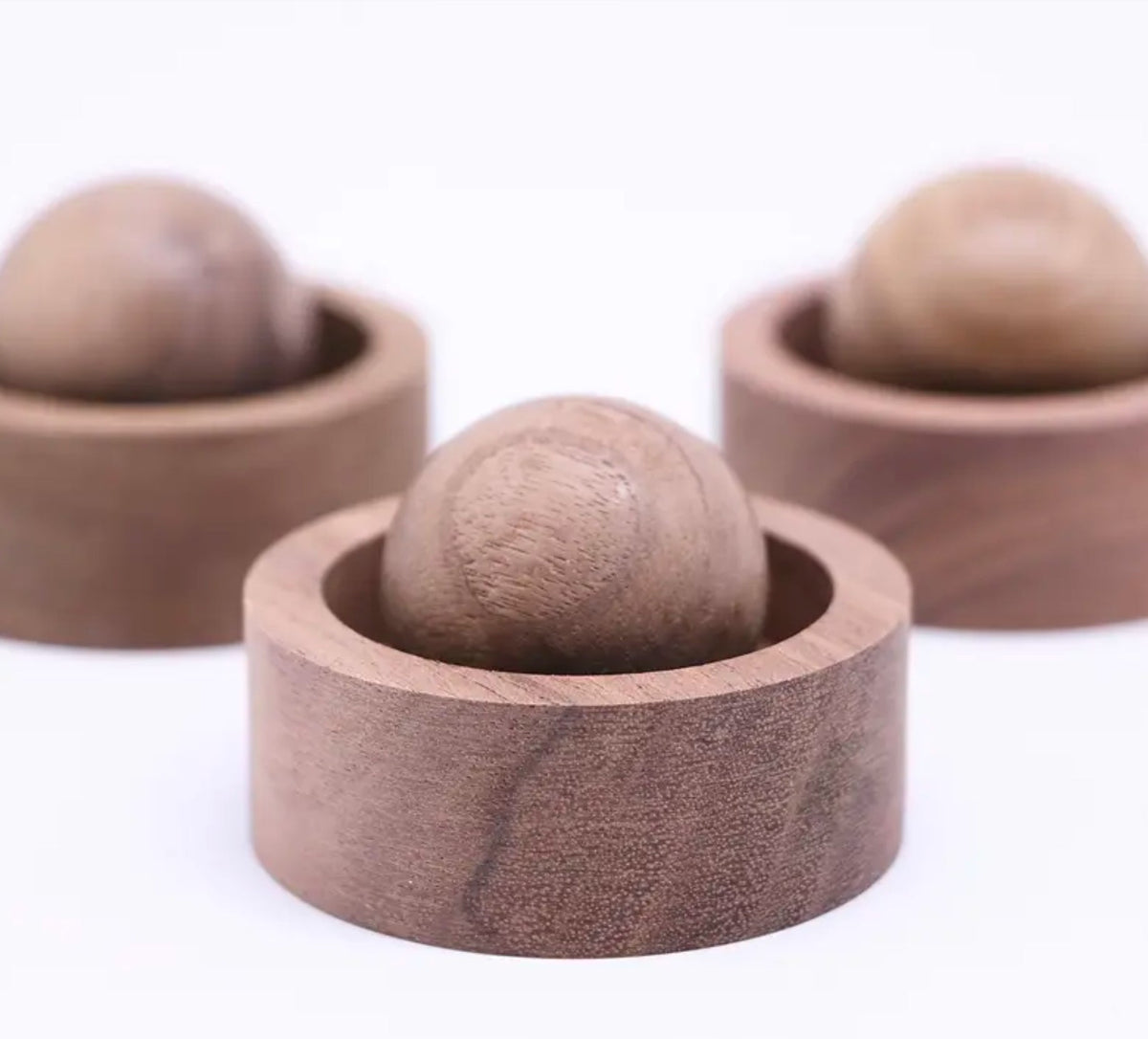 Three wooden containers with spherical wooden objects on a white background