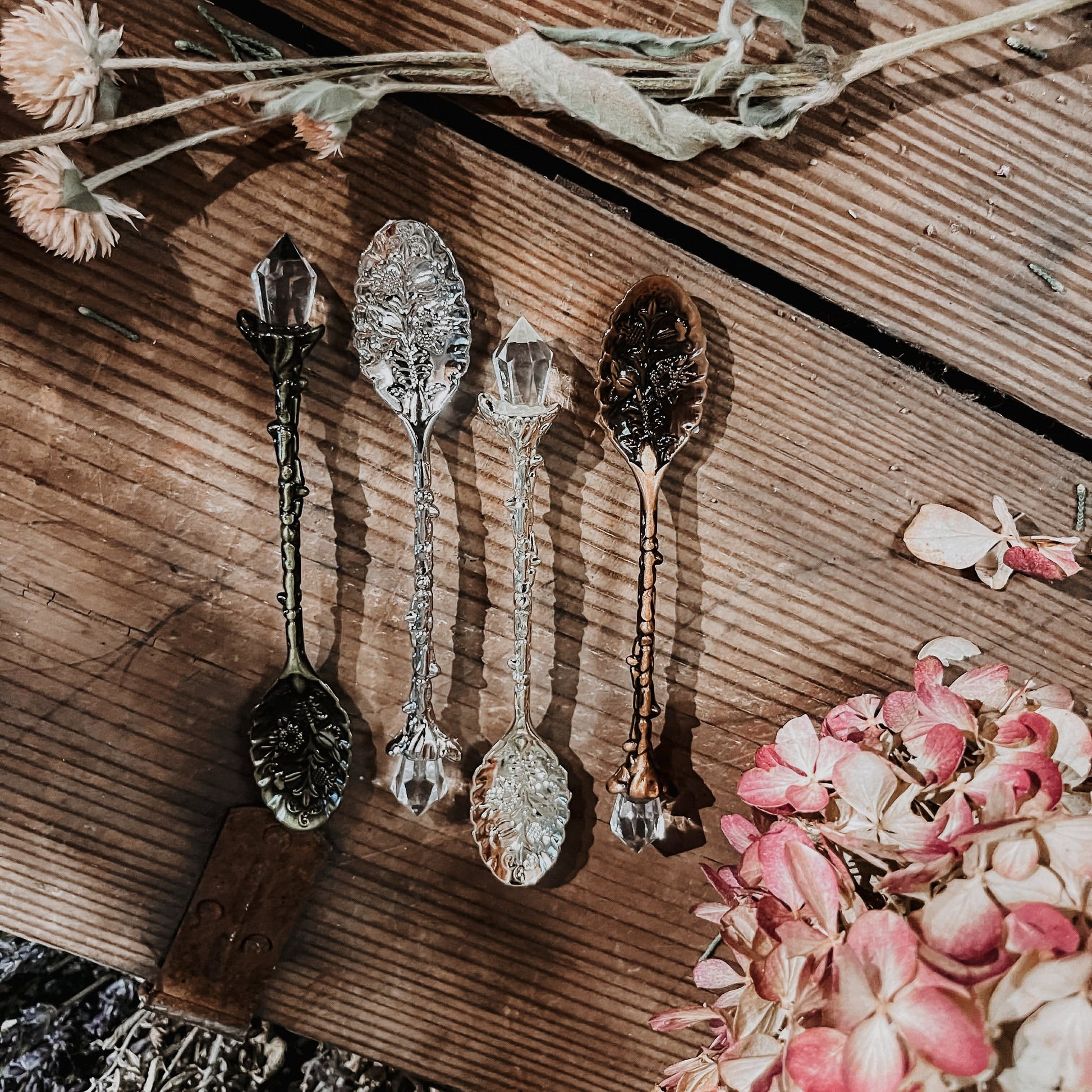 Decorative spoons with crystal handles on a wooden surface with flowers.