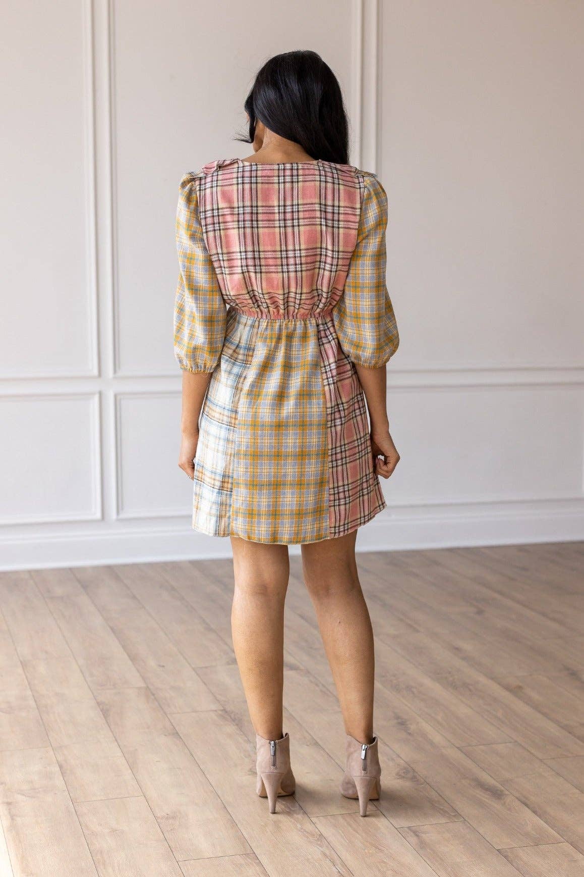 Woman wearing a plaid dress with a white wall background