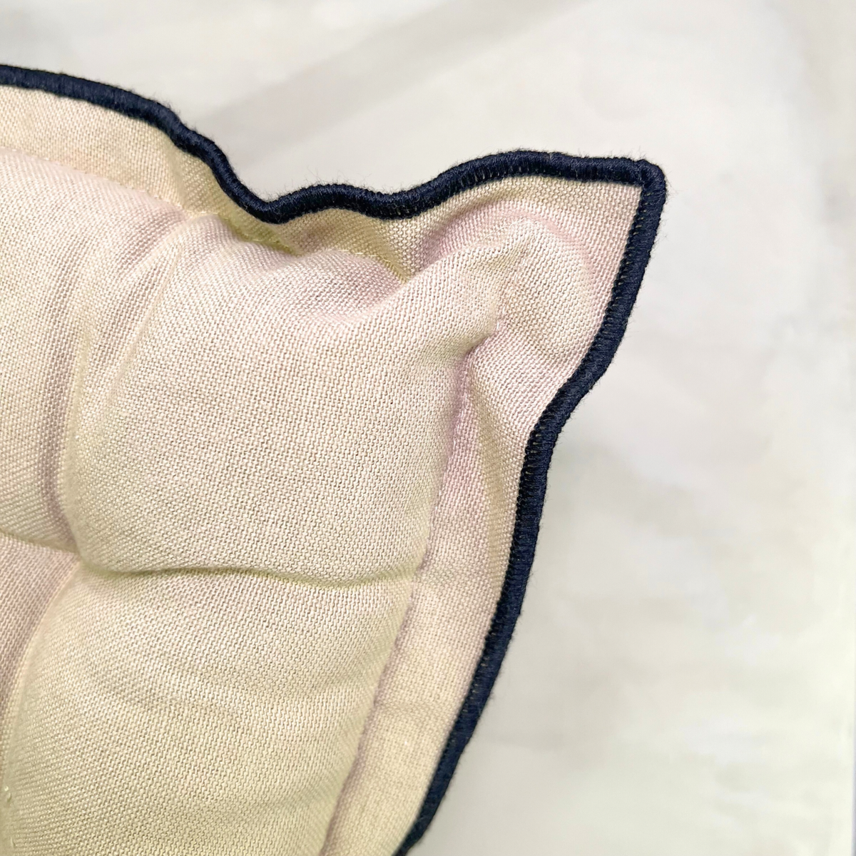 Close-up of a textured fabric with navy blue piping on a white background