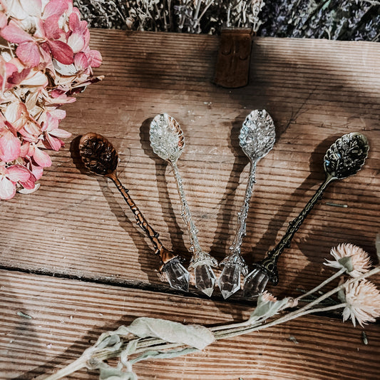 Decorative spoons on a wooden surface with flowers and plants.