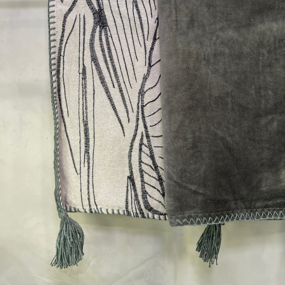 Two textured towels, one with a leaf pattern and tassels, on a light background