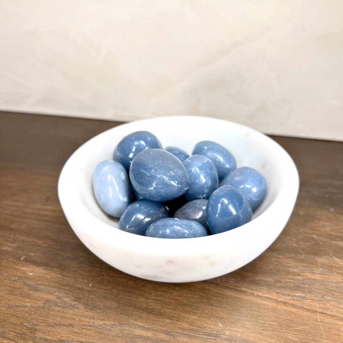 White bowl filled with blue stones on a wooden surface
