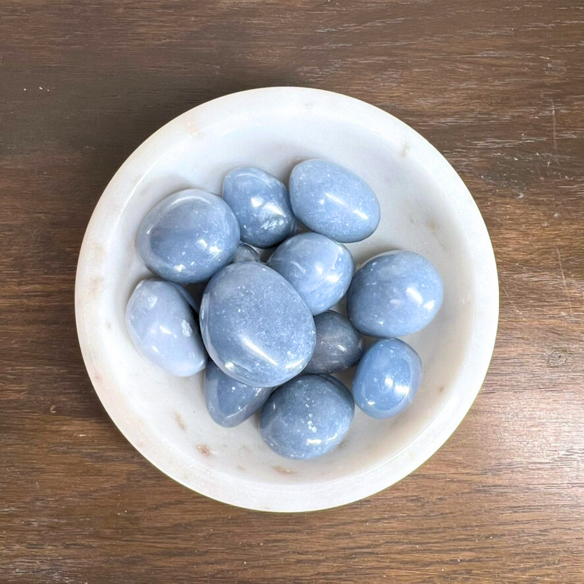 White bowl filled with blue stones on a wooden surface