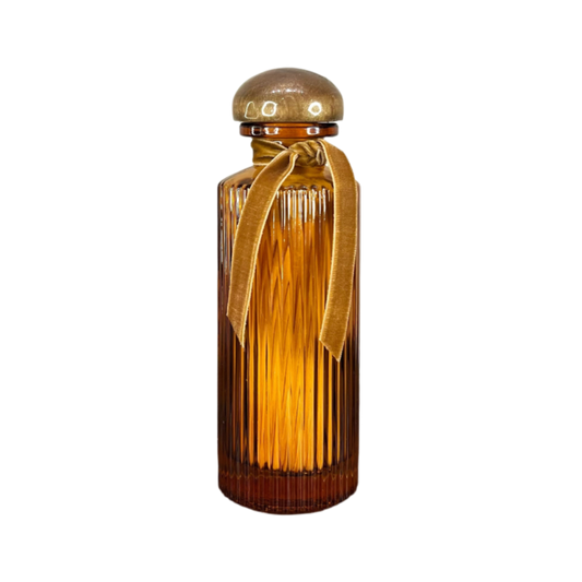 Decorative amber glass bottle with gold cap and ribbon on a white background