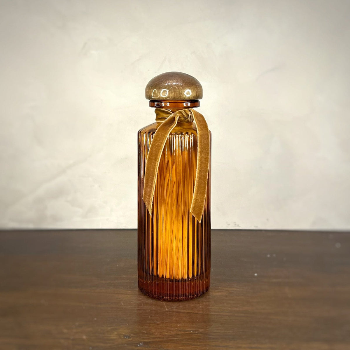 Brown glass bottle with a gold ribbon on a wooden surface