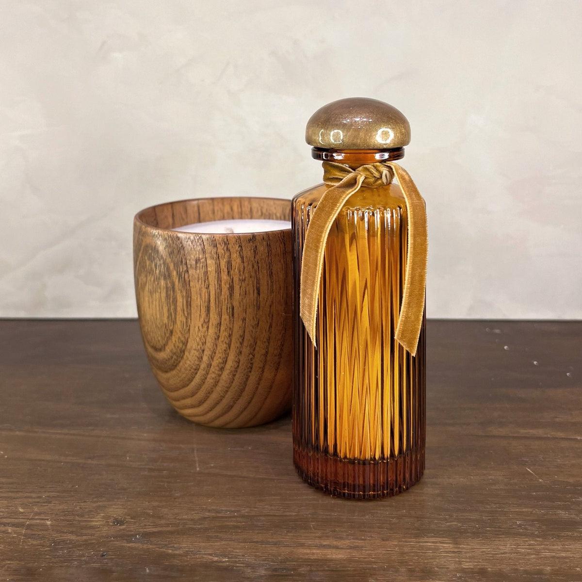 Brown glass carafe with a wooden lid and cup on a wooden surface