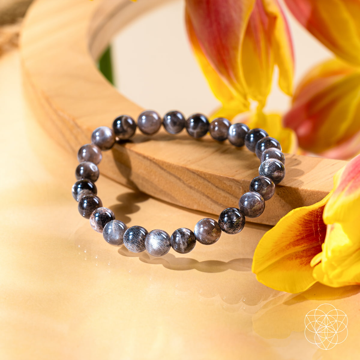 Silver beaded bracelet on a wooden surface with yellow flowers