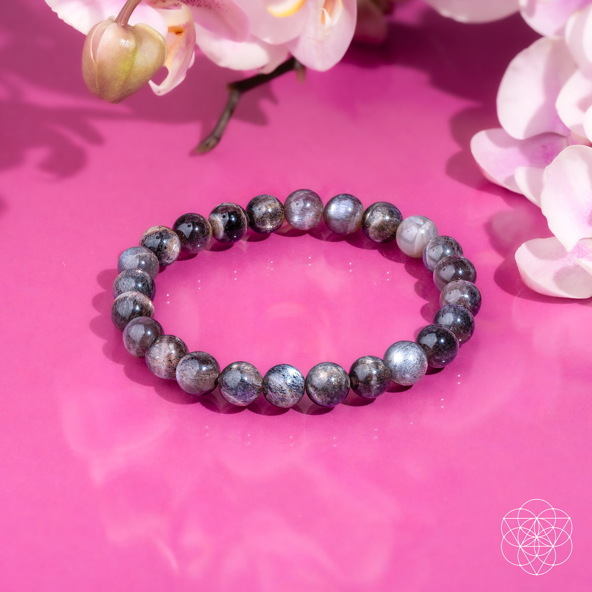 Beaded bracelet on a pink surface with flowers in the background