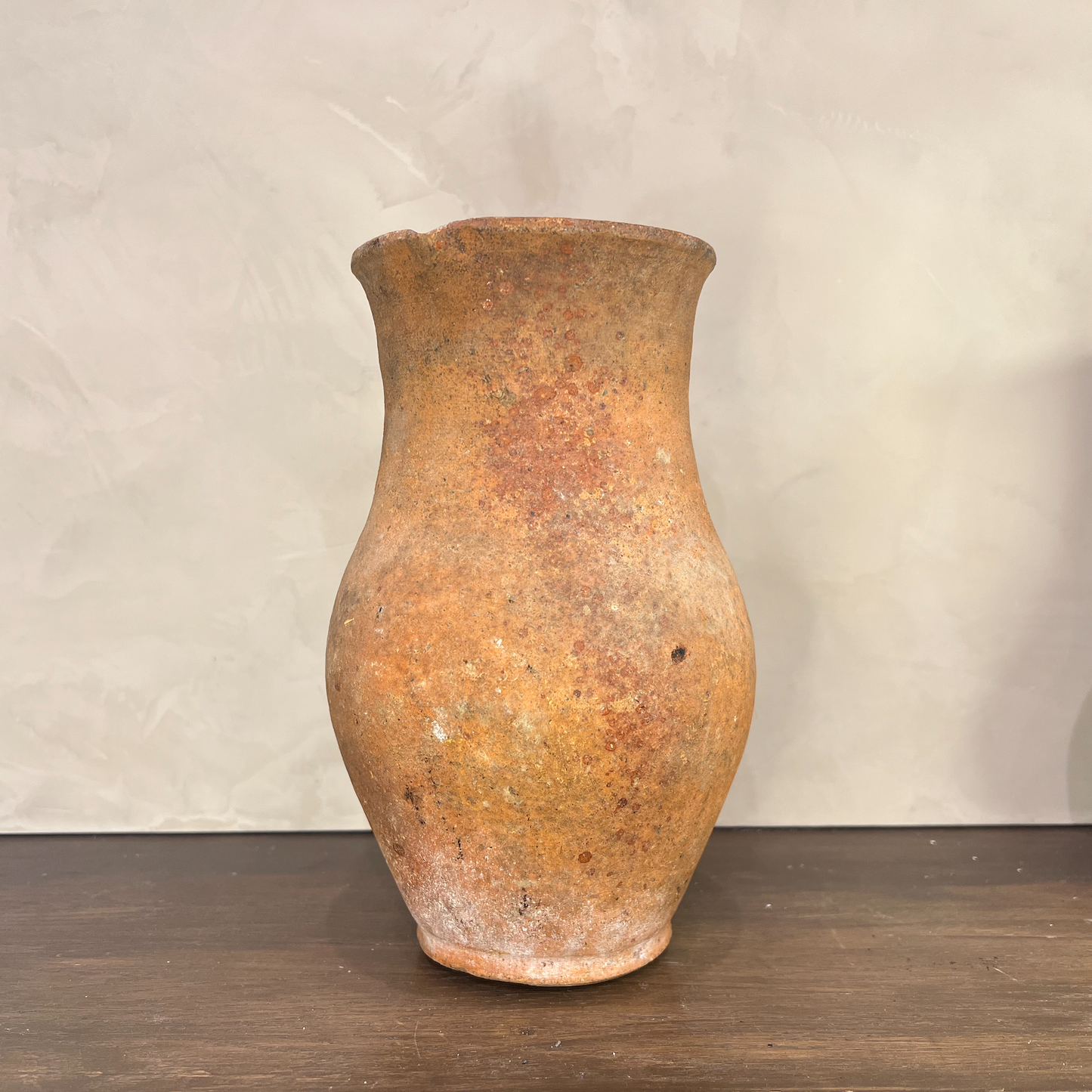 Vintage terracotta vase on a wooden surface with a plain background