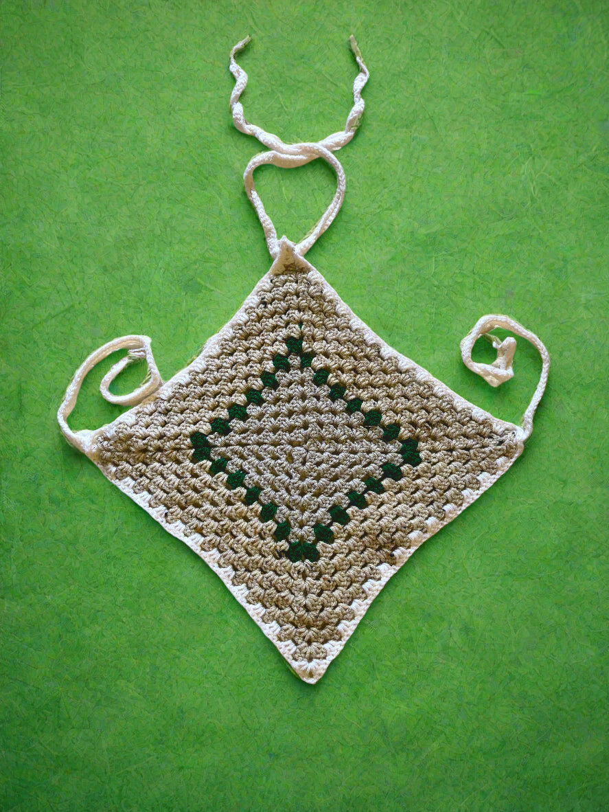 A handmade crochet top with a geometric diamond pattern, featuring adjustable straps and a tassel detail, displayed on a textured background.