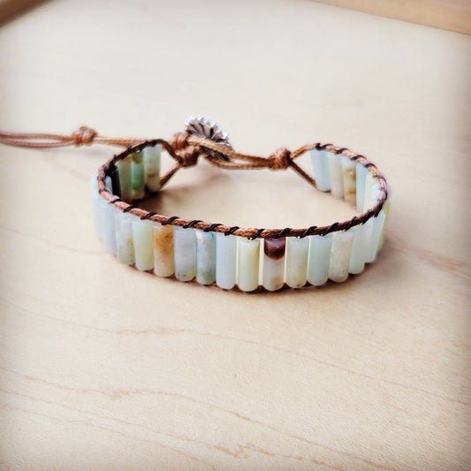 Bracelet with natural stone beads and brown cord on a light wooden surface