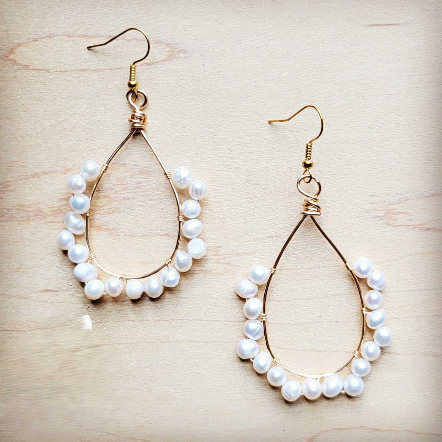 Pair of pearl hoop earrings on a light wooden surface