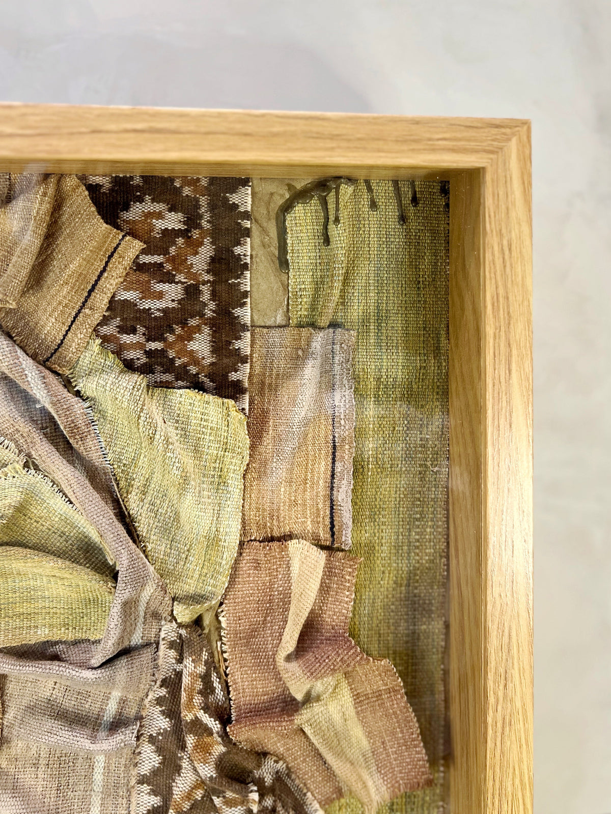 Textile sample with various patterns and colors in a wooden frame.