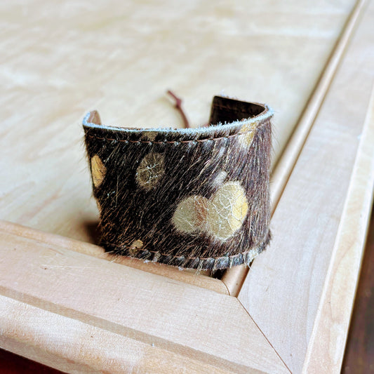 Textured brown leather cuff bracelet on a wooden surface