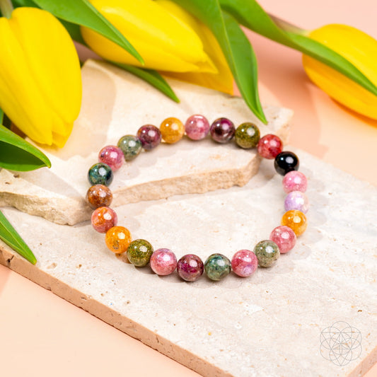 Multicolored beaded bracelet on a textured surface with yellow tulips in the background