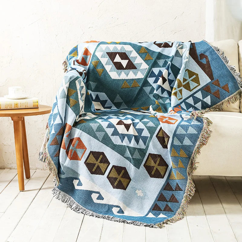 Geometric patterned blanket draped over a chair in a room with a wooden table and white walls.