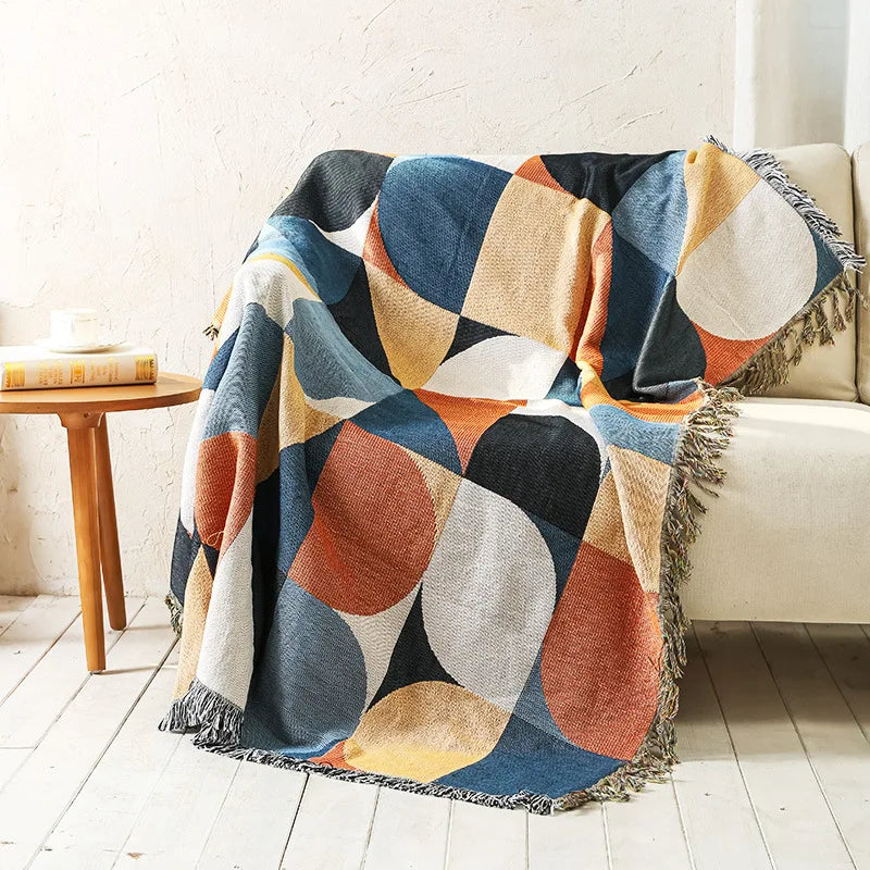 Colorful geometric-patterned throw blanket draped over a couch in a living room.
