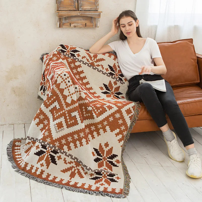 Patterned throw blanket draped over a brown sofa in a living room.