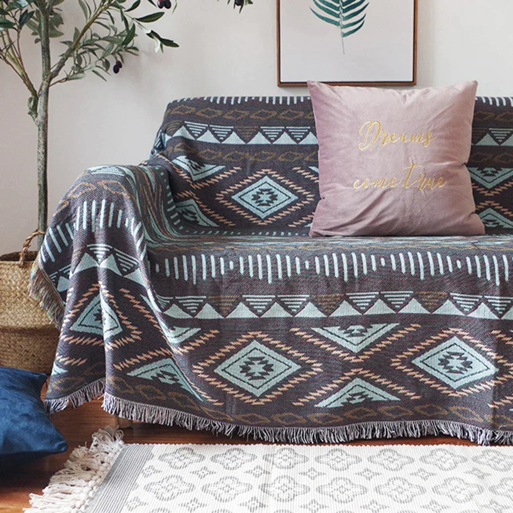 Sofa with patterned throw blanket and pink pillow in a living room setting