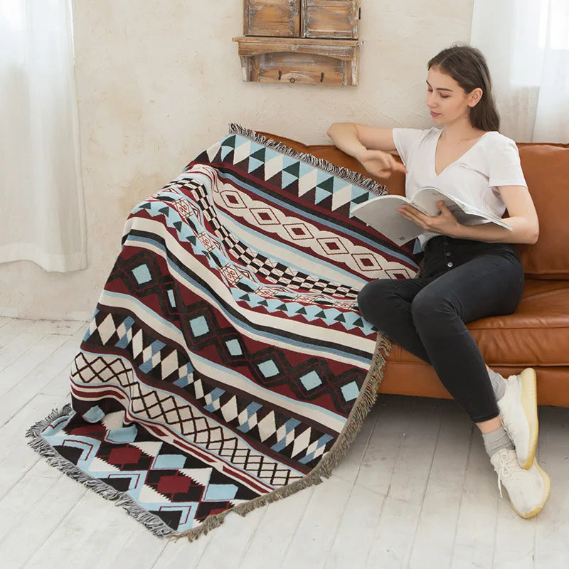 Woman reading a book on a couch with a patterned blanket
