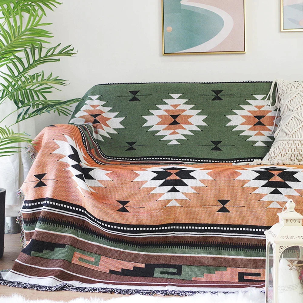 Patterned throw blanket draped over a couch in a living room setting with a plant and artwork.
