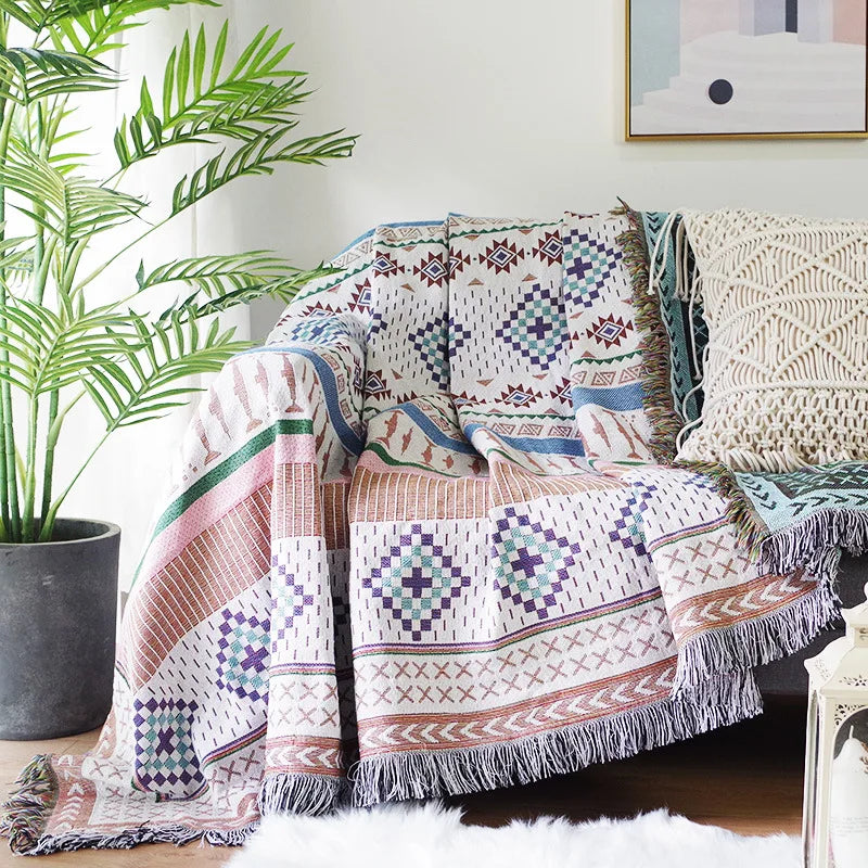 Patterned throw blanket draped over a sofa with a plant and decorative items in the background