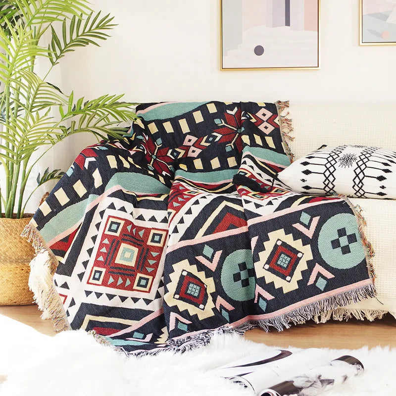 Geometric patterned throw blanket on a couch with a plant and framed pictures in the background