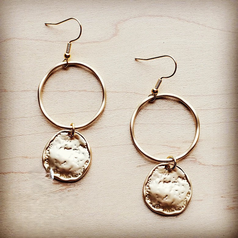 Gold hoop earrings with circular pendants on a wooden surface